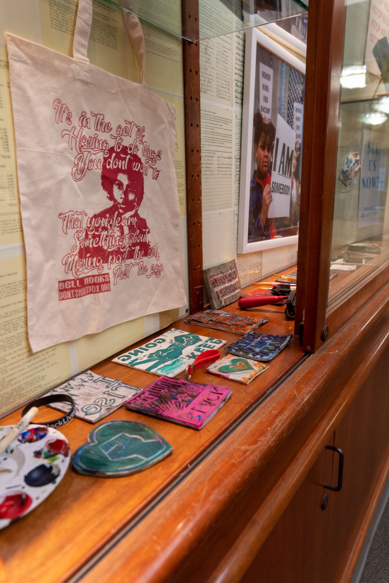 Case exhibiting Community Art projects, specifically "Bag Swag" distributed at Don't Shoot PDX to encourage art practice within the social justice movement